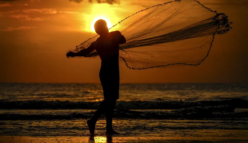 Pescador lanzando red al agua.